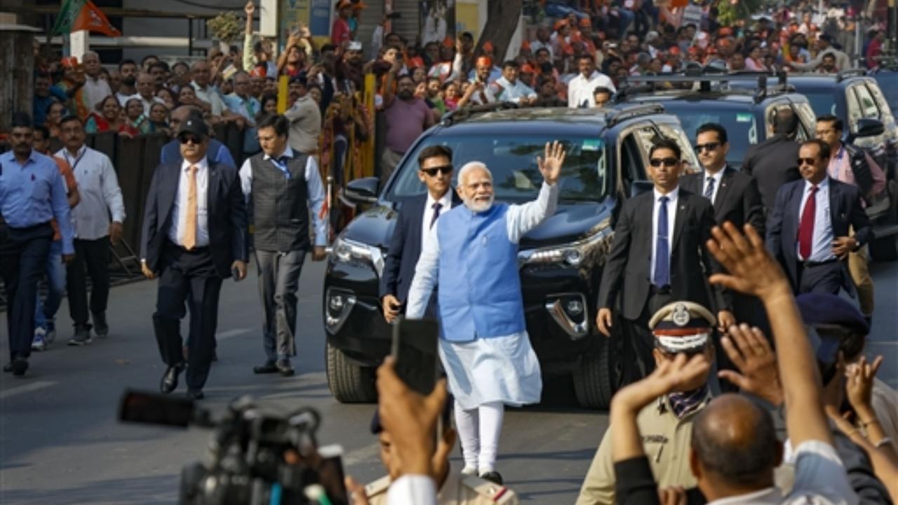 Prime Minister Narendra Modi waves at supporters as he leaves after casting his vote at a polling booth during the second and final phase of Gujarat assembly elections, at Ranip area in Ahmedabad