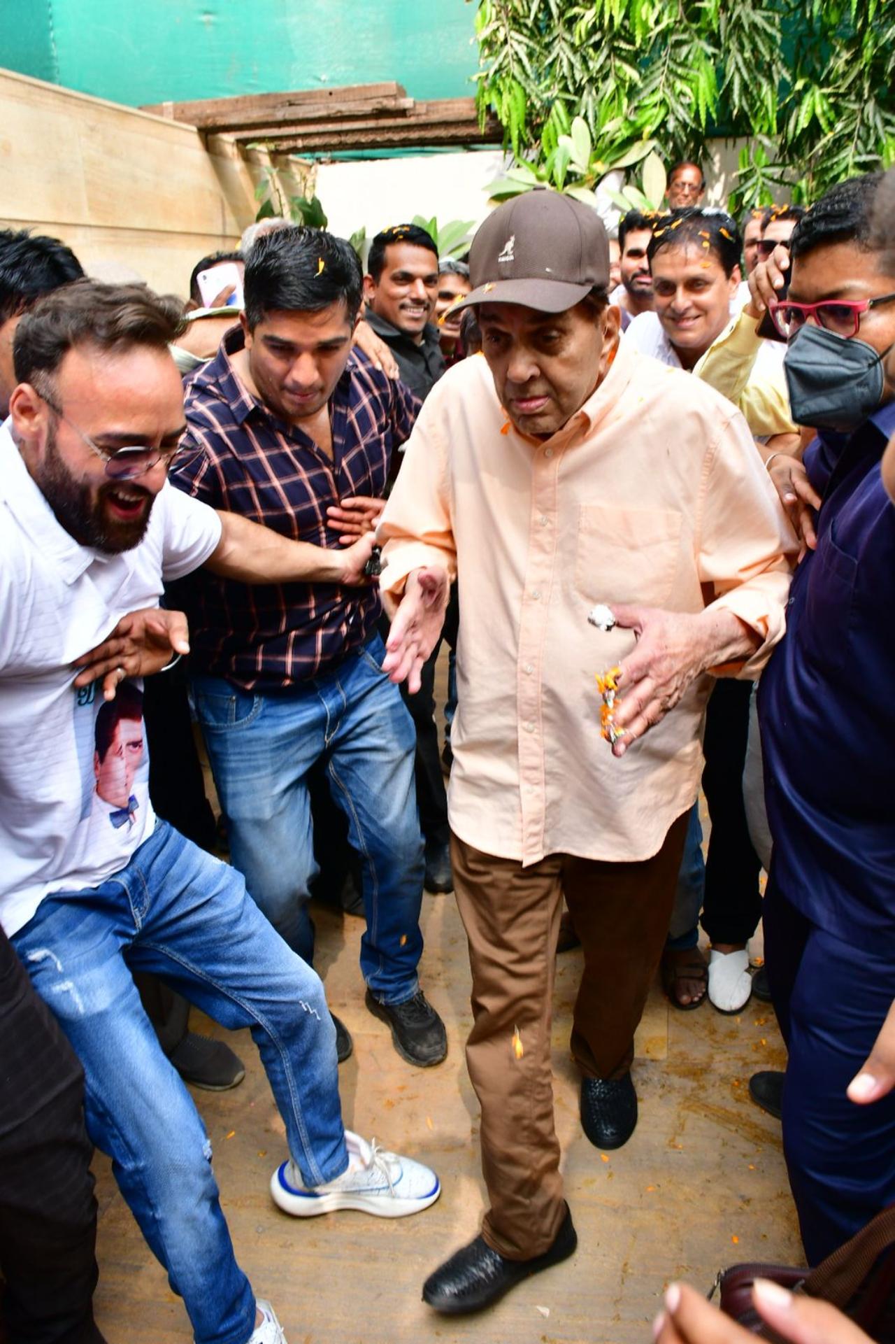 Dharmendra stepped out in a blush pink shirt and brown pants with a cap for the cake cutting