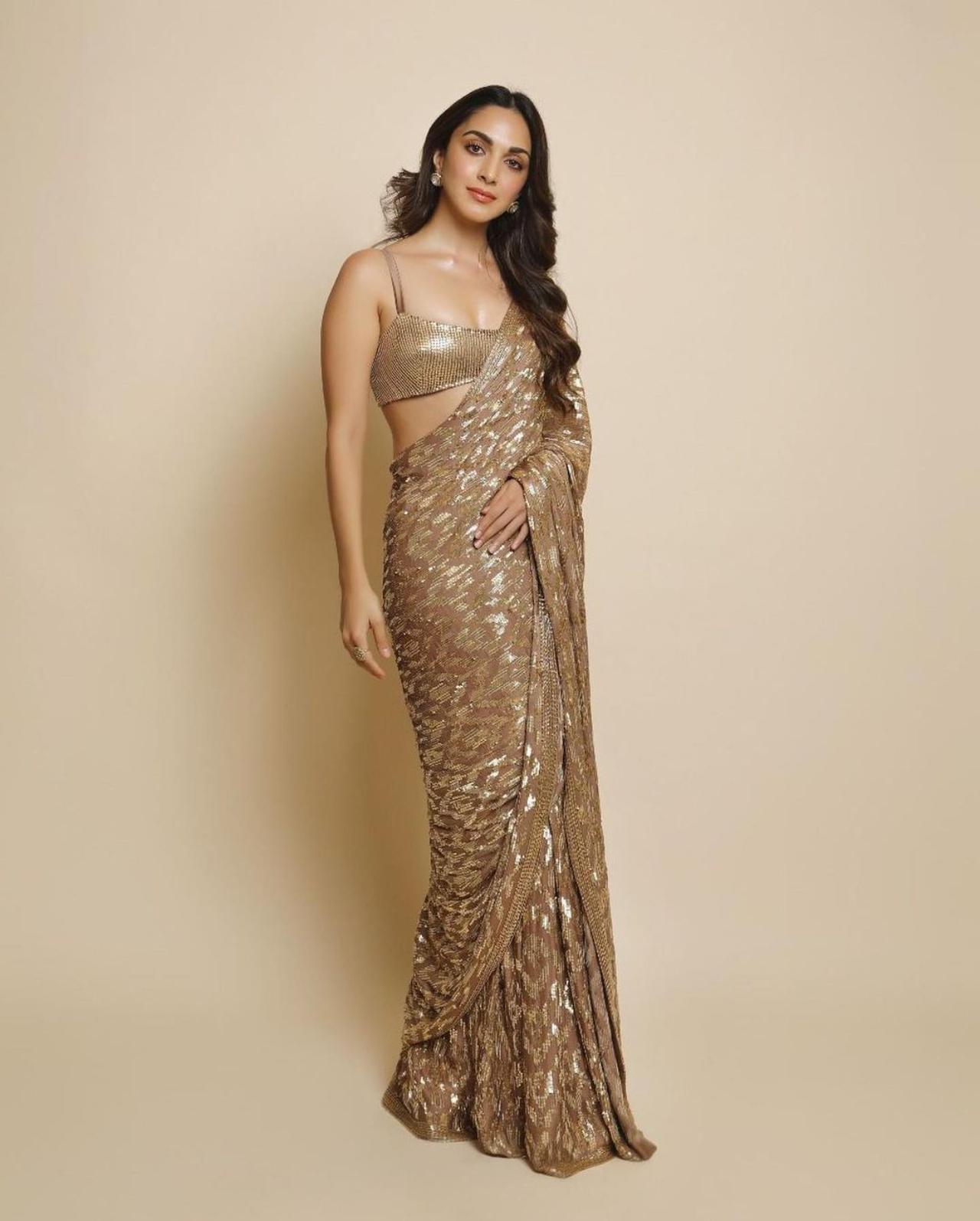 Kiara Advani looks stunning in this bronze gold mettalic saree. She completed the look with glossy make-up and round earrings