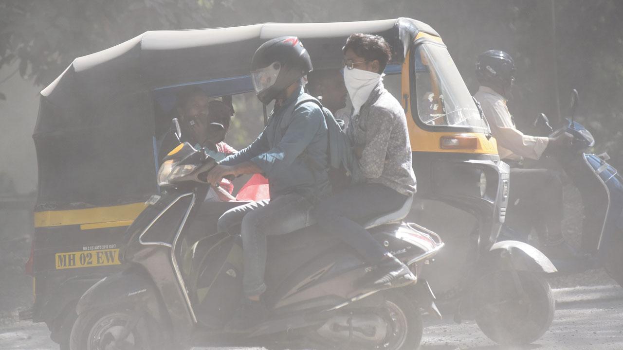 People cover their face for protection against dust from the roadwork, in Aarey Colony, on Friday