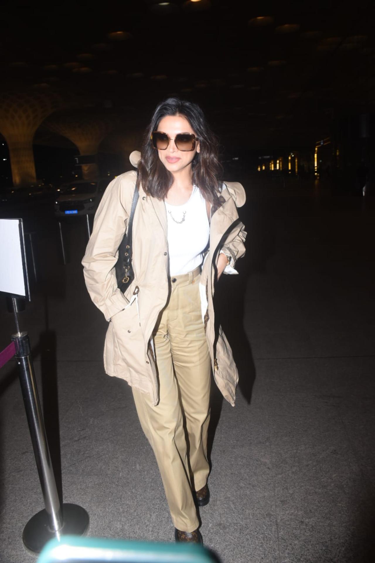 On Saturday morning, Deepika was seen at the airport dressed in a white top, khakee trench coat and matching pants. She left her hair open and had black shades on. The actress was all smiles as she waved to the paparazzi