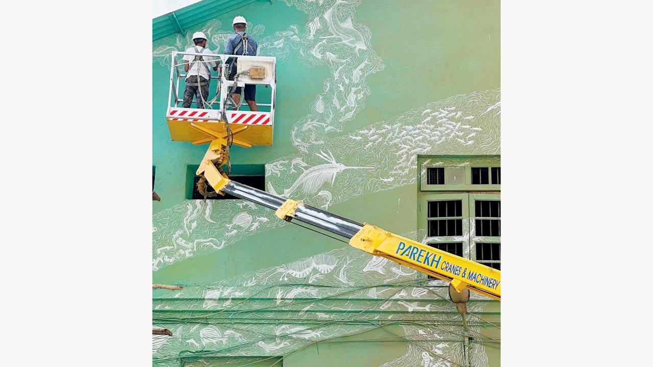 Vayeda’s team works on the mural across the central building