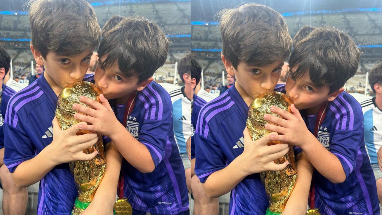 Mateo Messi Roccuzzo and Thiago Messi Roccuzzo kissing the FIFA World Cup trophy