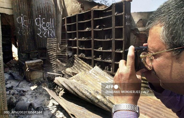 An insurance company surveyor takes photographs of burned shops to evaluate shopowners' claims at Delhi Darwaza in Ahmedabad March 5, 2002