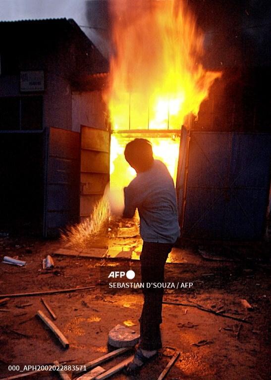 A shop owner tries to douse the flames as the entire wood market was set ablaze at Lathi Bazar, in Ahmedabad on February 28, 2002