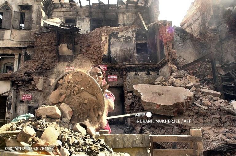 A woman works through the wreckage of a burnt house in Ahmedabad, March 7, 2002. Residents of the city started to rebuild damaged properties and shops following the worst clashes in nearly a decade