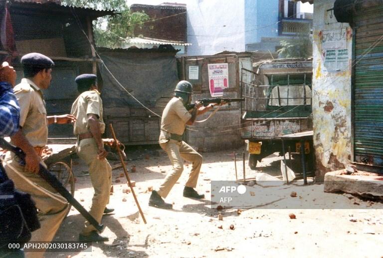 A policeman aims at an angry mob at Millat Nagar in Ahmedabad on March 1, 2002