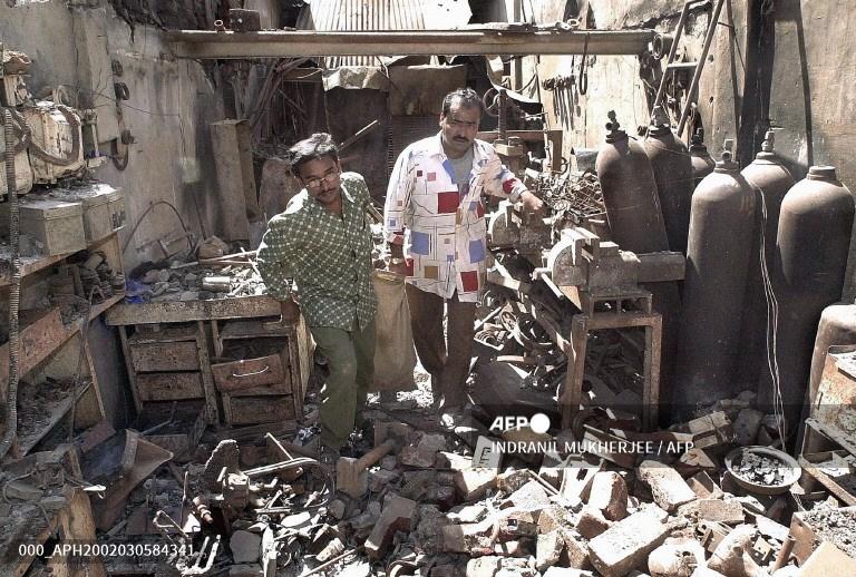 Ahmed (L) and his brother Amin (R) salvage goods from their burned shop in Ahmedabad on March 5, 2002