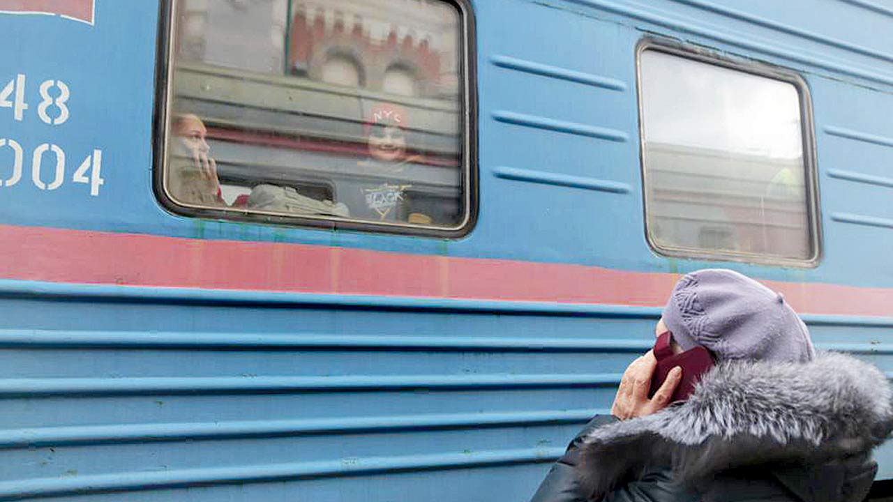 A woman speaks on the phone with her relatives as a child looks through a train window prior to being evacuated to Russia, in Debaltseve which is controlled by pro-Russian militants, Ukraine, on Saturday. Pic/AP