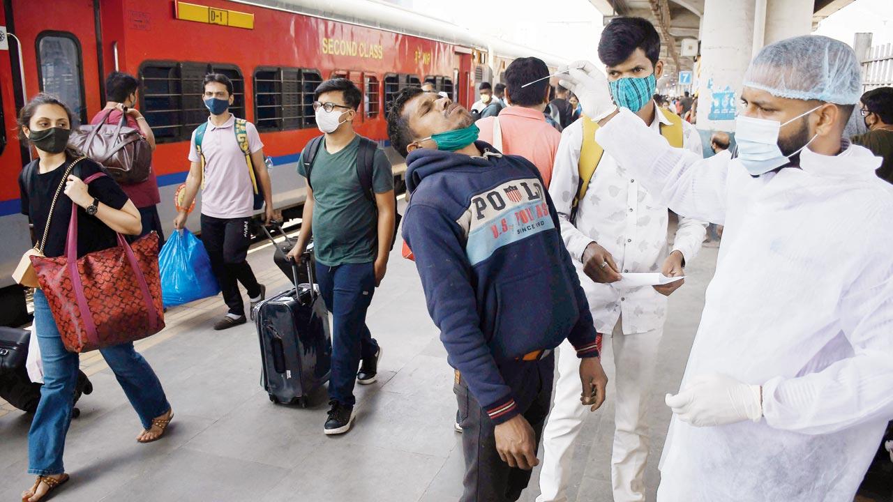 A BMC health worker tests a passenger arriving at Dadar station on Sunday. Pic/Ashish Raje