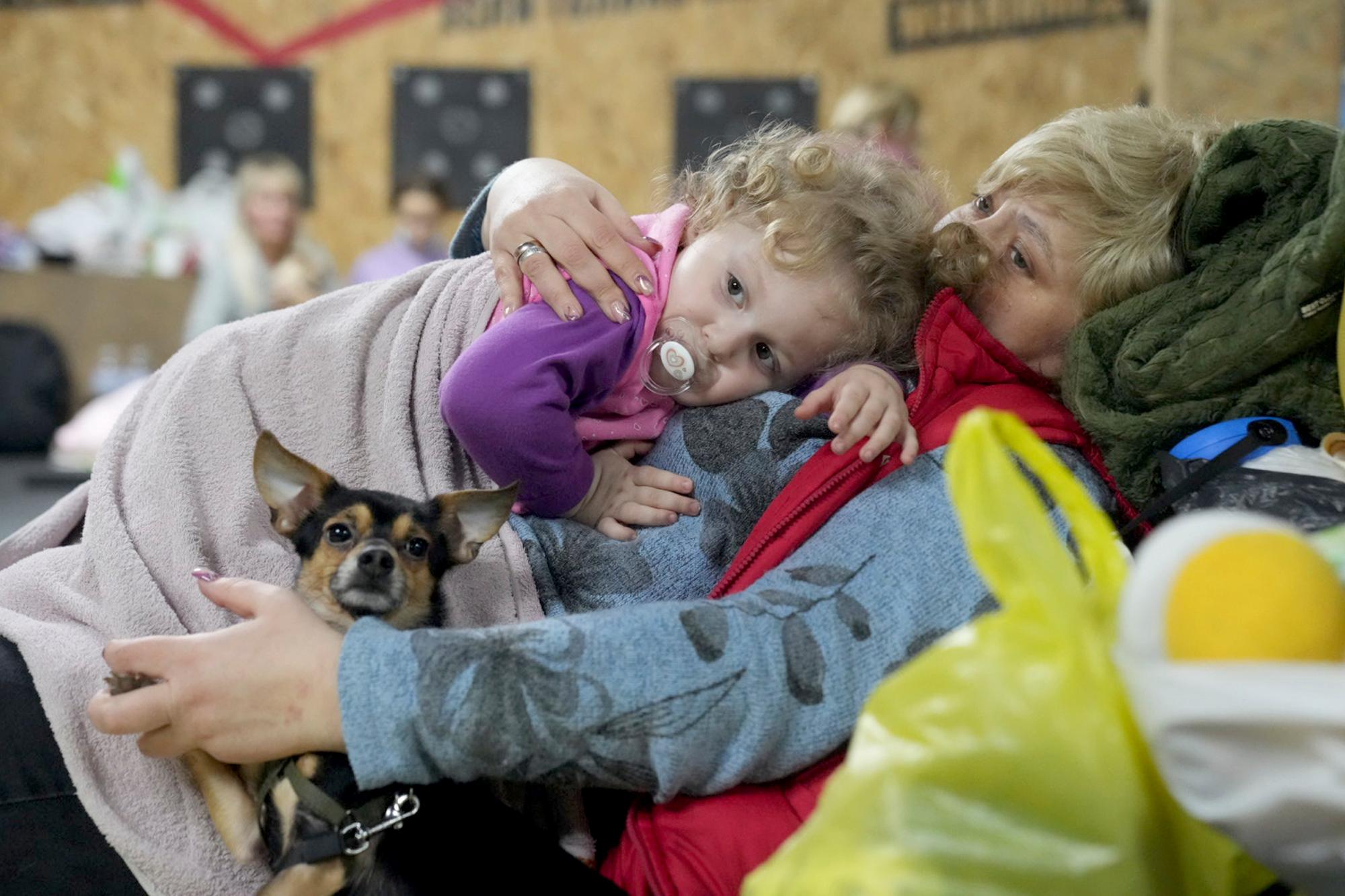 A women holds a child and a dog in a shelter inside a building in Mariupol, Ukraine, Feb. 27, 2022. Street fighting broke out in Ukraine's second-largest city and Russian troops squeezed strategic ports in the country's south as the prospect of peace talks remains uncertain. Pic/PTI