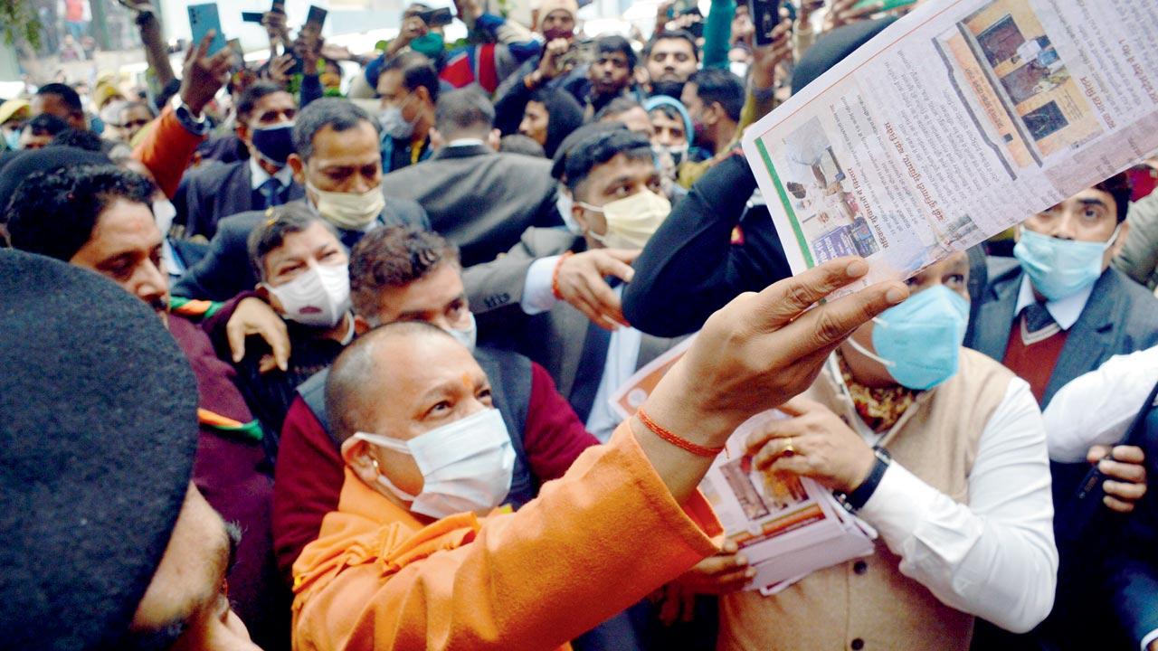 UP CM Yogi Adityanath distributes BJP pamphlets during a party election campaign, in Ghaziabad on Sunday. Pic/ANI