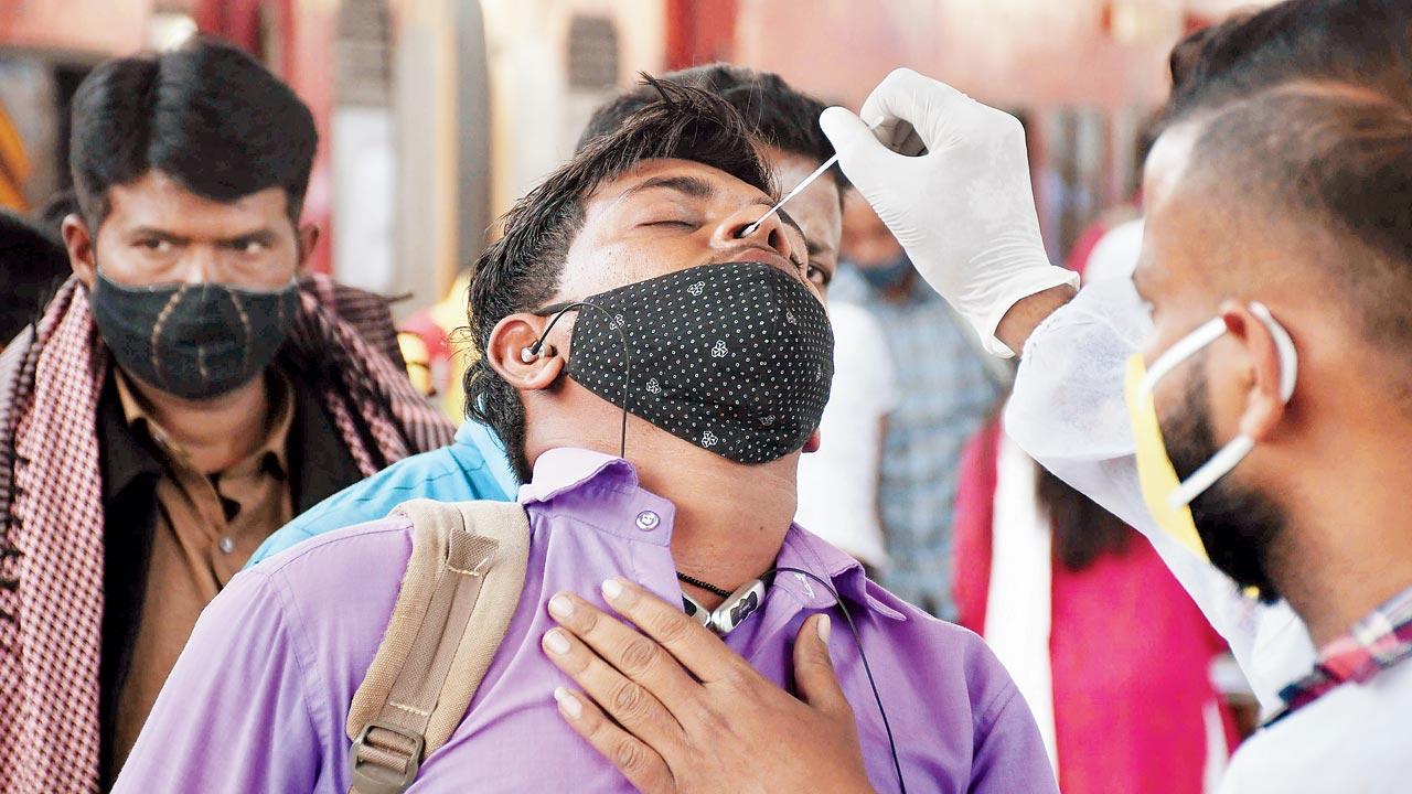 A BMC health worker tests a passenger for COVID-19 at Dadar station on Sunday. Pic/Ashish Raje
