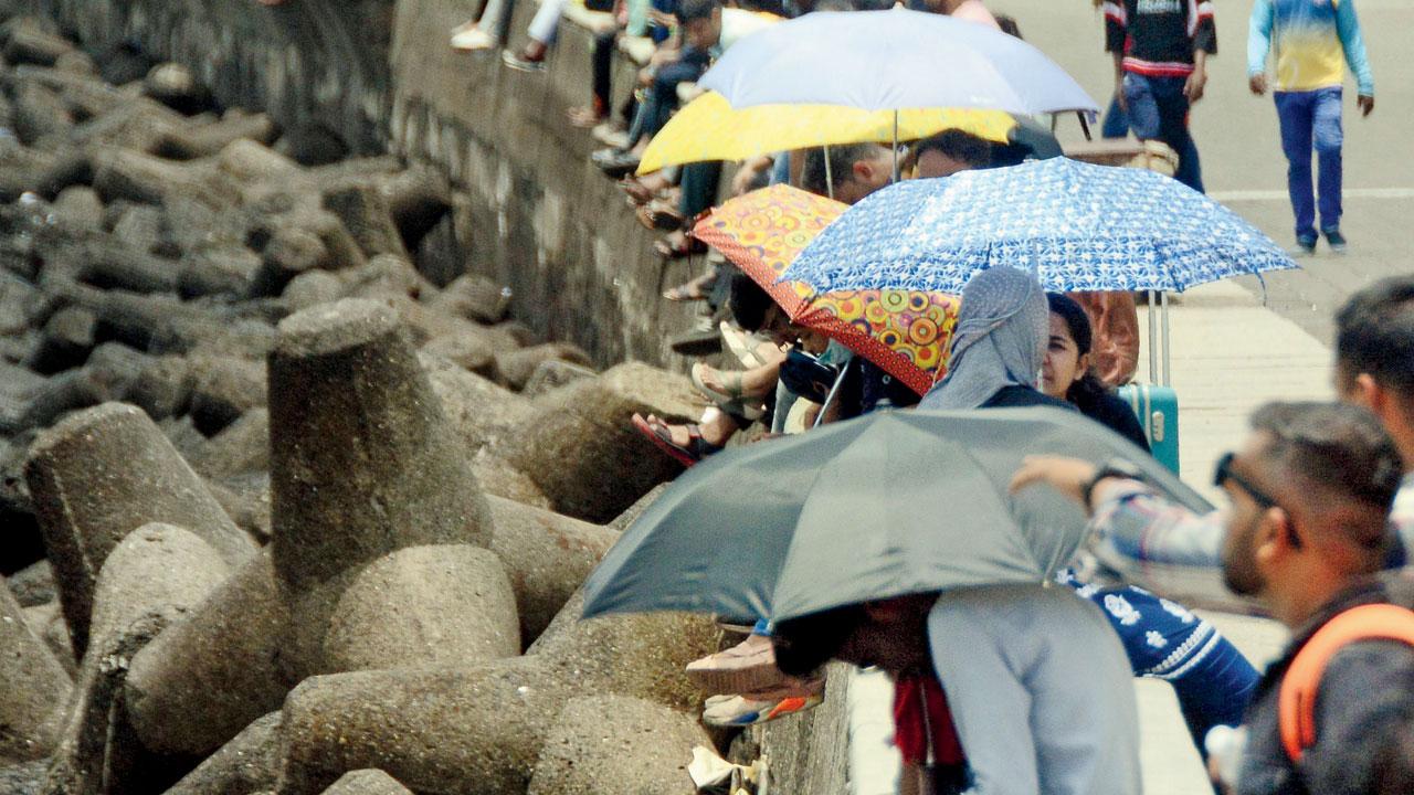 Youngsters use umbrellas to protect them from heat on a seafront, July 28. Pic/Sayyed Sameer Abedi