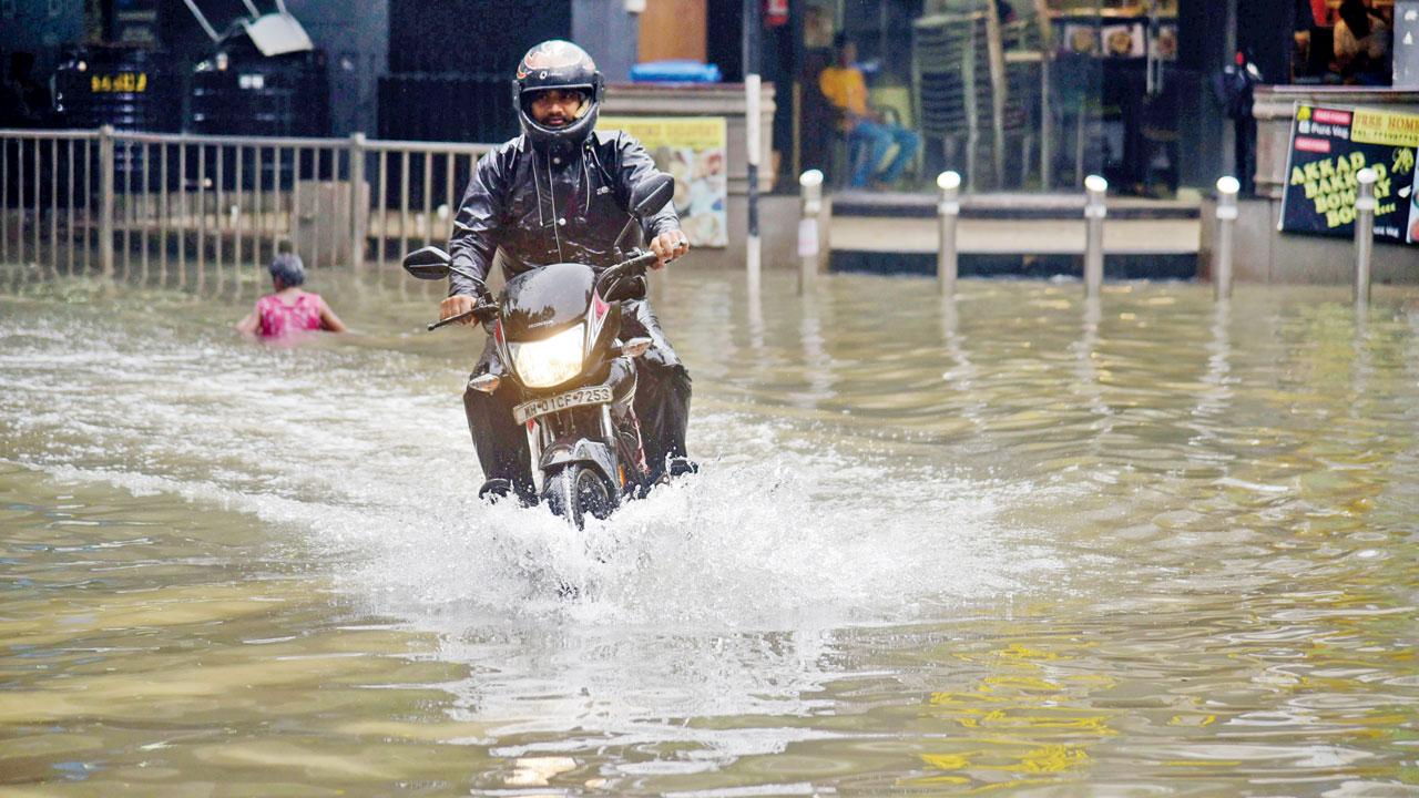 Commuters navigate a waterlogged road, after a heavy rainfal, in Sion, on Tuesday. Pic/Atul Kamble
