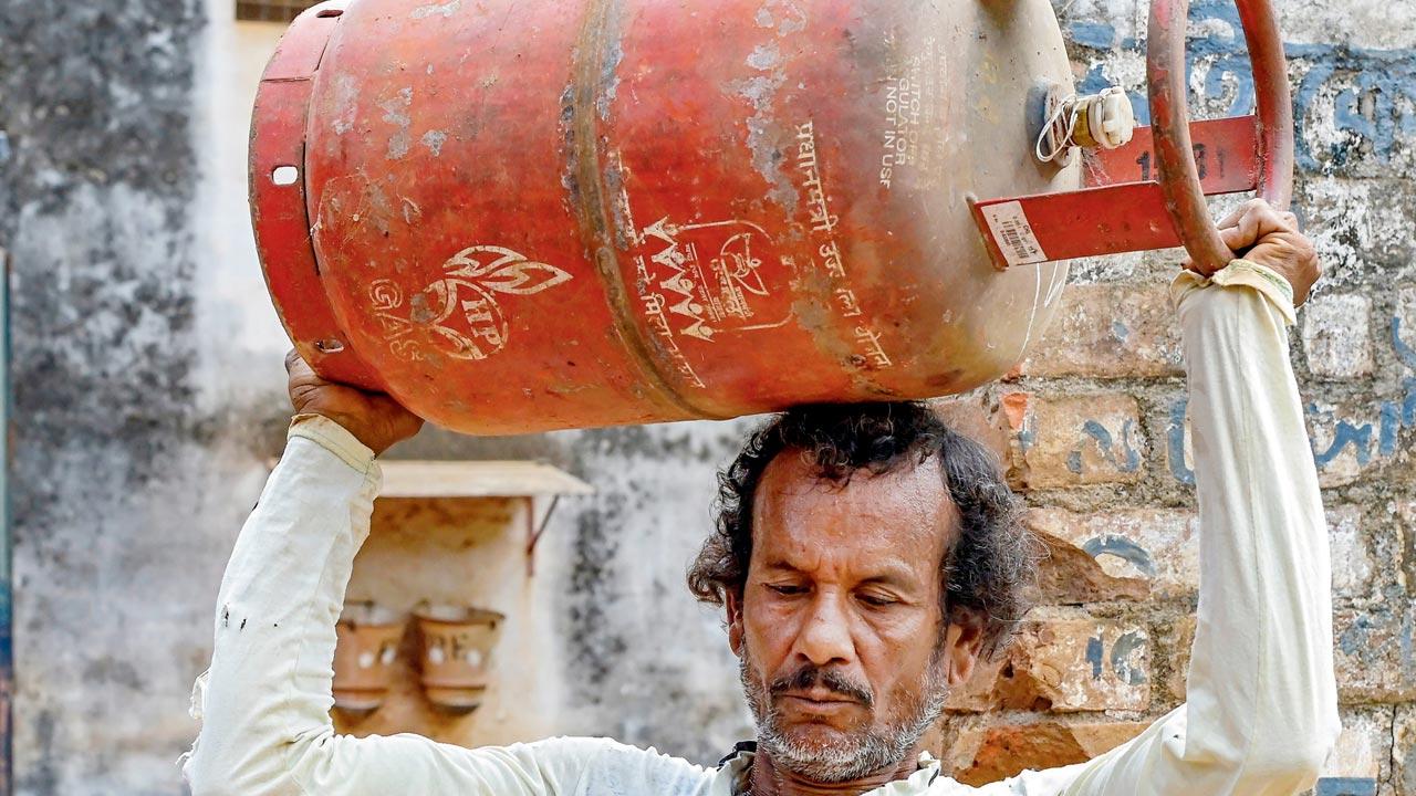 A man carries an LPG cylinder in Nadia, Bengal, on Wednesday. PIC/PTI