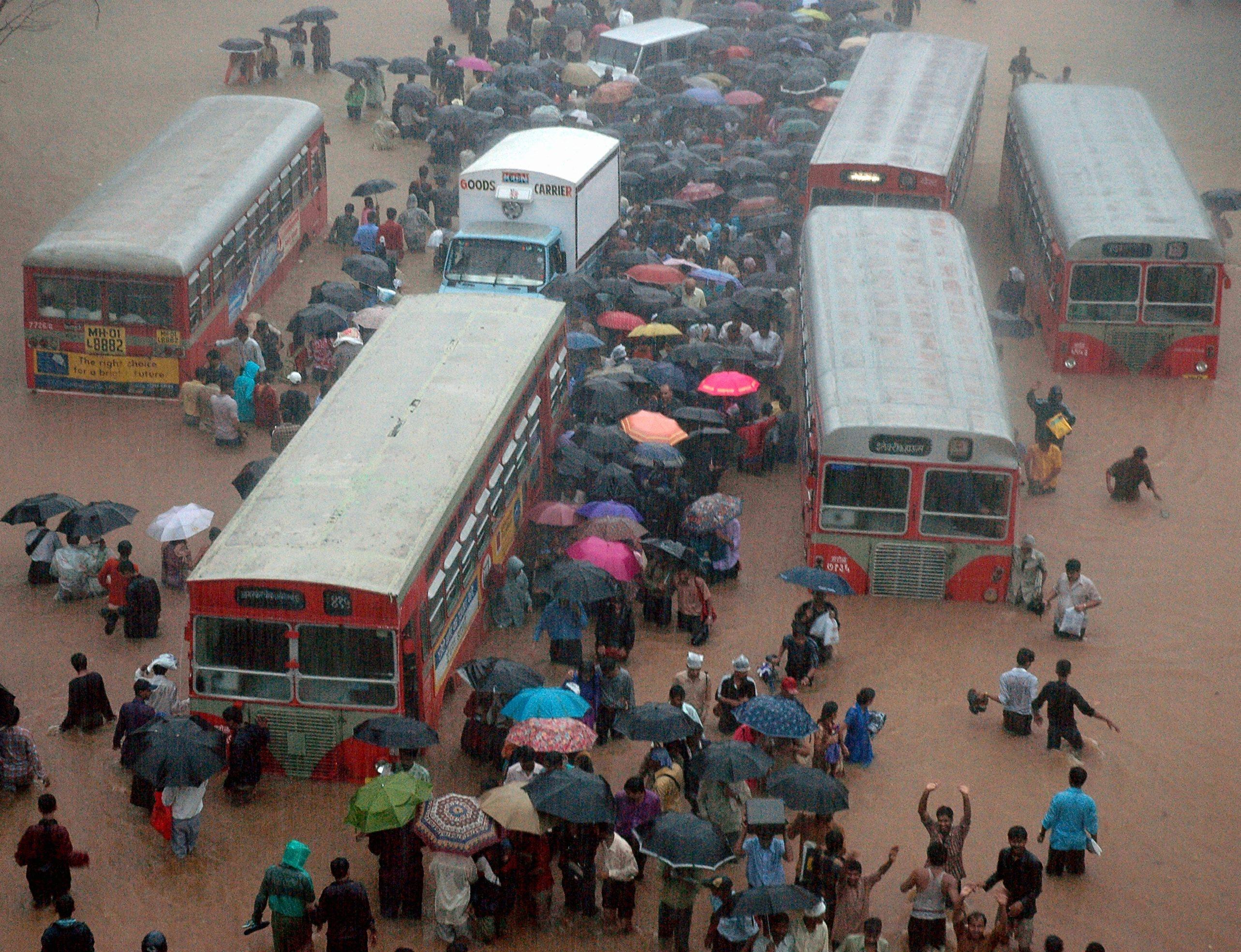 Commuters walk past stranded vehicles after heavy rains brought Mumbai to a halt.