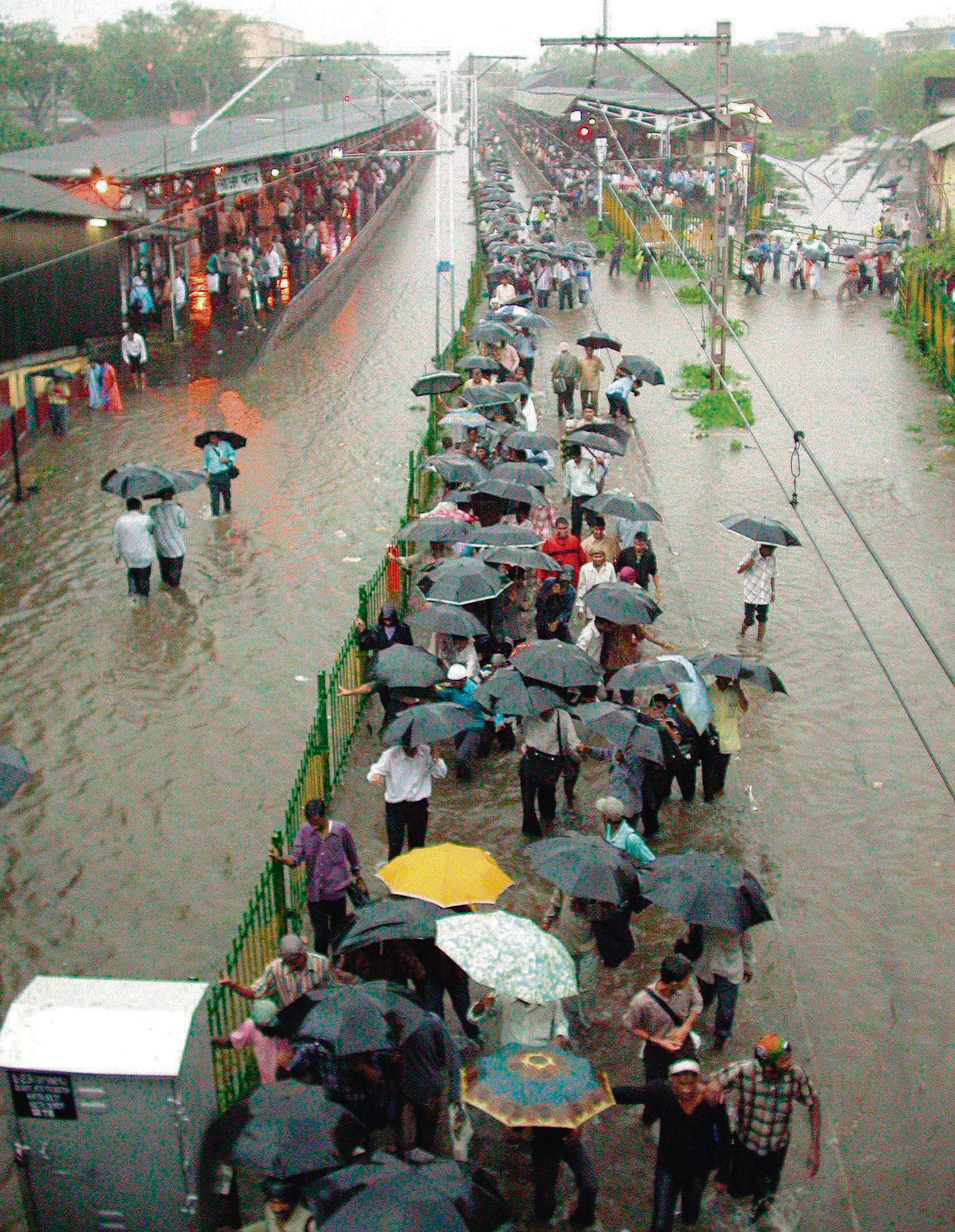 People walk on the waterlogged railway tracks during the July 26, 2005 floods.