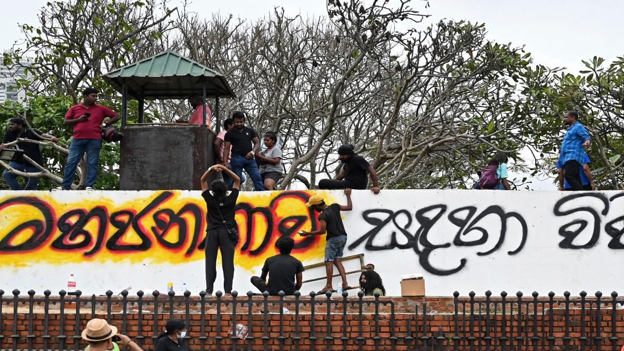 People paint slogans on the boundary wall of the official residence of Sri Lanka's Prime Minister, in Colombo