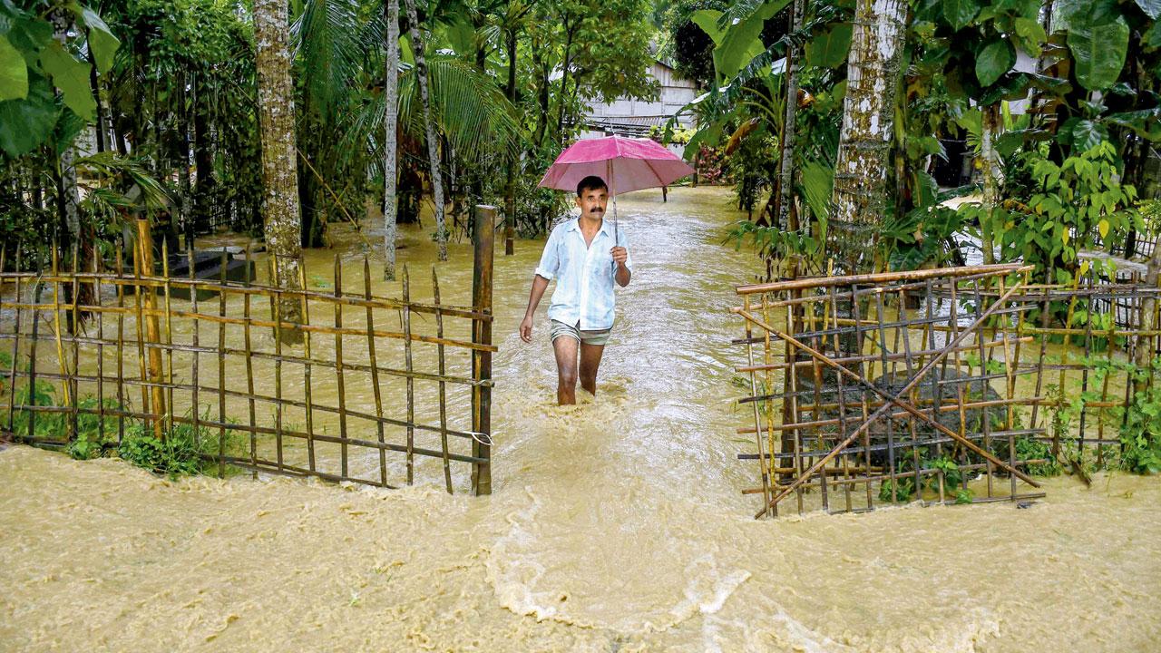 A villager wades through a flooded road in Assam. PIC COURTESY/PTI