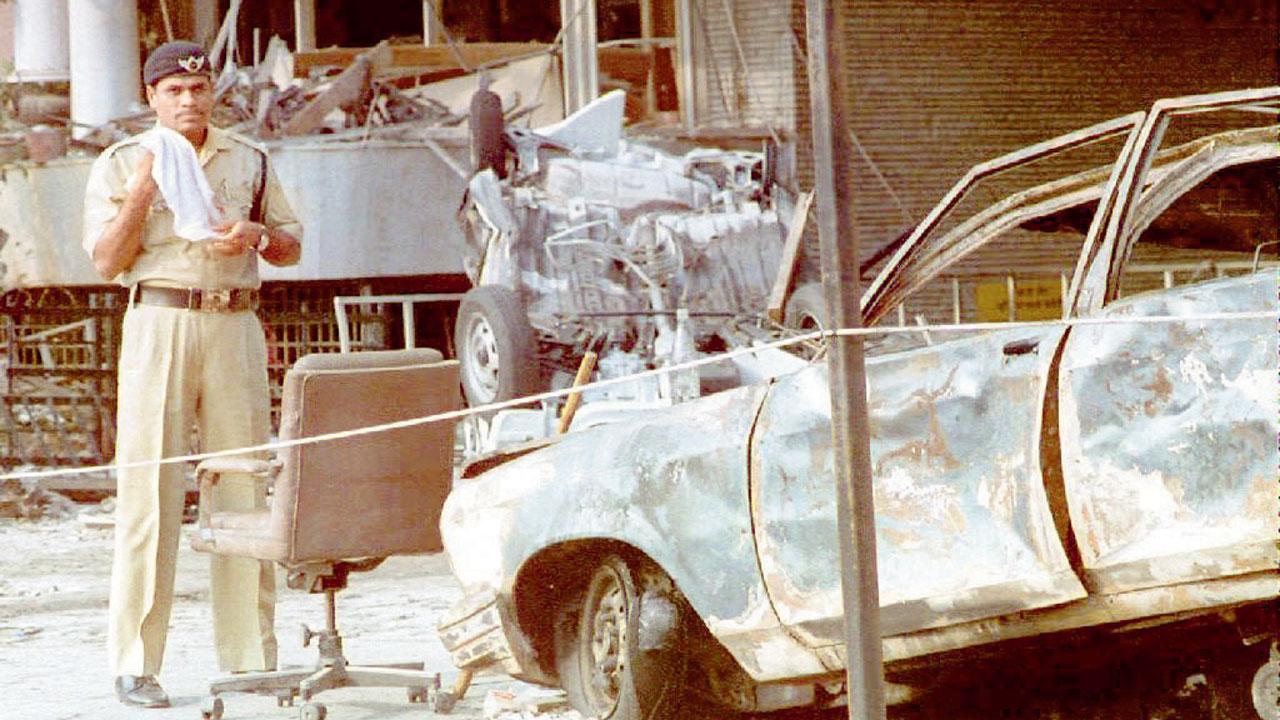 A cop stands beside a charred car outside the Air India building, after a series of bombings, on 14 March 1993. Pic/AFP