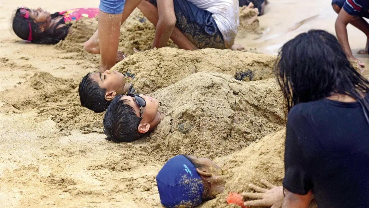 Cover me in sand shine: Children and their parents play the buried in the sand game on Juhu beach on Thursday. Pic/Atul Kamble