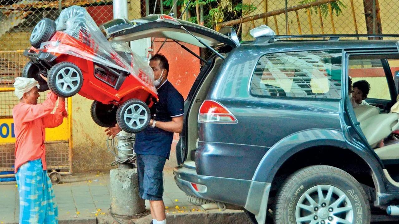 Curious car obar: A man tries to fit a toy car into his SUV at Crawford Market while his child looks on. Pic/Satej Shinde