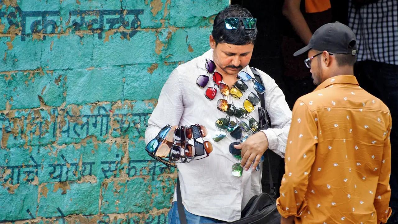 Shady business: A vendor turns display model to sell sunglasses at the Gateway of India. Pic/Ashish Raje