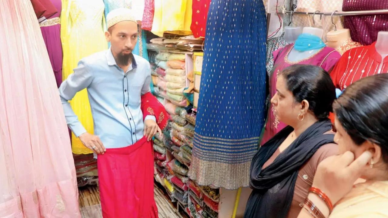Will go to any lengths: A salesperson in a garments shop in Malad does his best to convince a couple of interested customers. Pic/Anurag Ahire