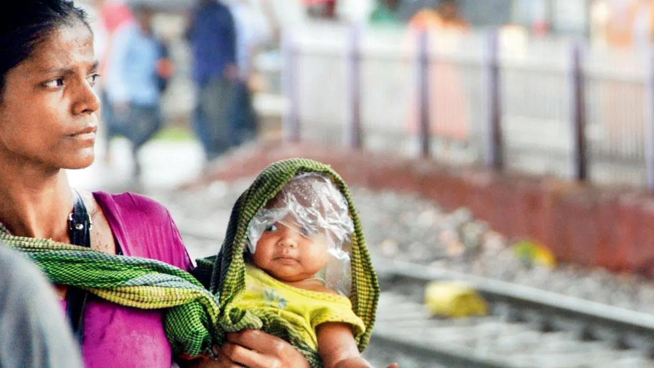 Look, it's ma' raincoat: A mother covers her little one’s head with a plastic sheet underneath her dupatta while negotiating Diva station on a rainy Monday. Pic/Satej Shinde