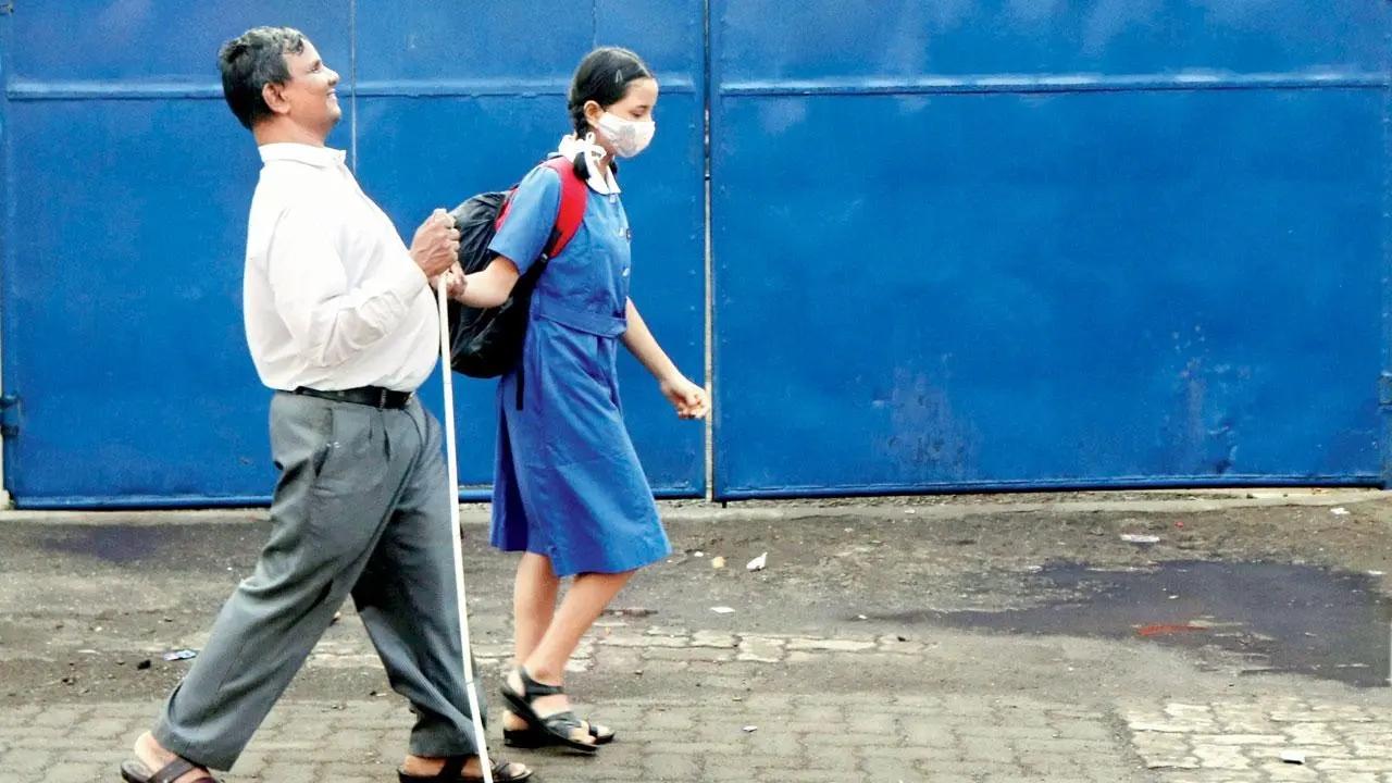Blue is the warmest colour: A schoolgirl escorts a blind man in Andheri East. Pic/Anurag Ahire