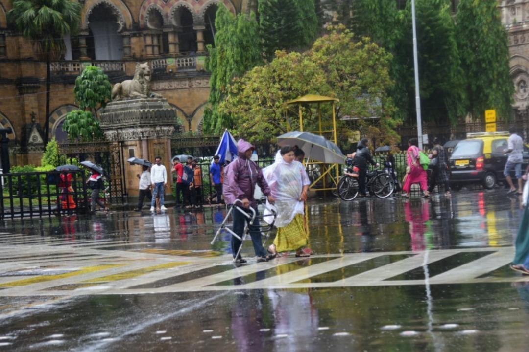 People holding umbrellas walk on a road amid rainfall, in Mumbai. Pic/Pradeep Dhivar