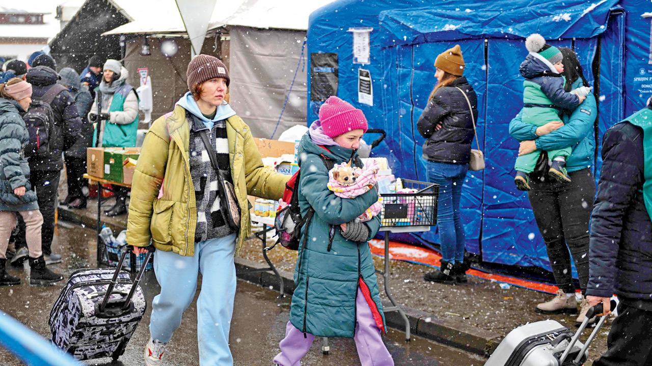 Refugees coming from Ukraine walk next to shelter tents at the Ukrainian-Romanian border in Siret, on Wednesday
