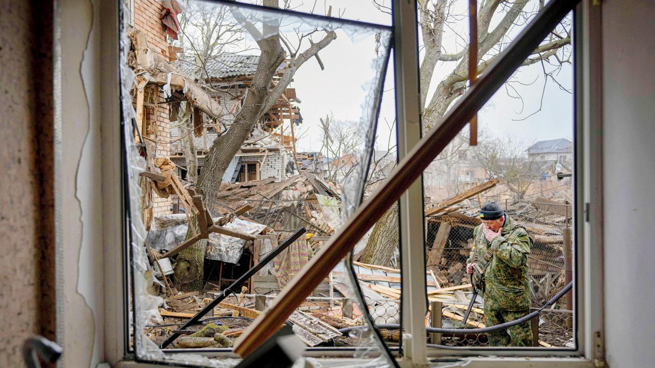 A member of territorial defence wipes his face in the backyard of a house that was damaged by a Russian airstrike, in Gorenka, outside the capital city of Kyiv, Ukraine, on Wednesday. Pic/AFP