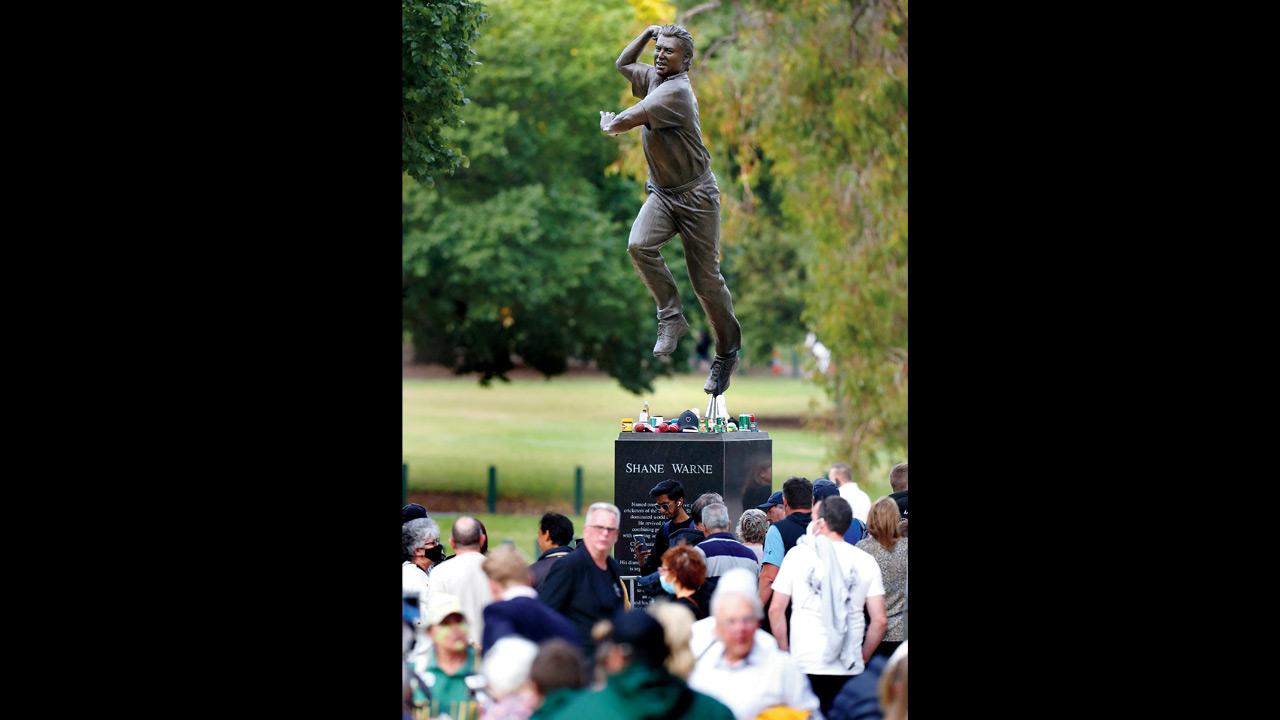 People gather around the statue of Shane Warne before the state memorial service at Melbourne Cricket Ground yesterday