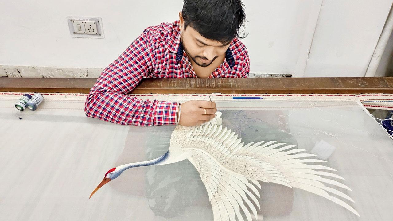 A karigar works on the Oriental-style panels celebrating the flying crane, which will be showcased at the venue