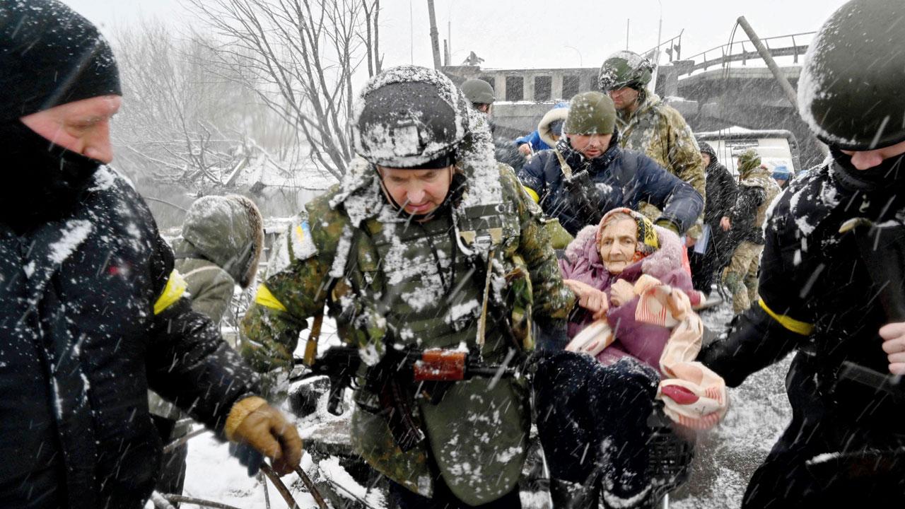 Irpin: Ukrainian soldiers help an elderly woman as she evacuates on Tuesday