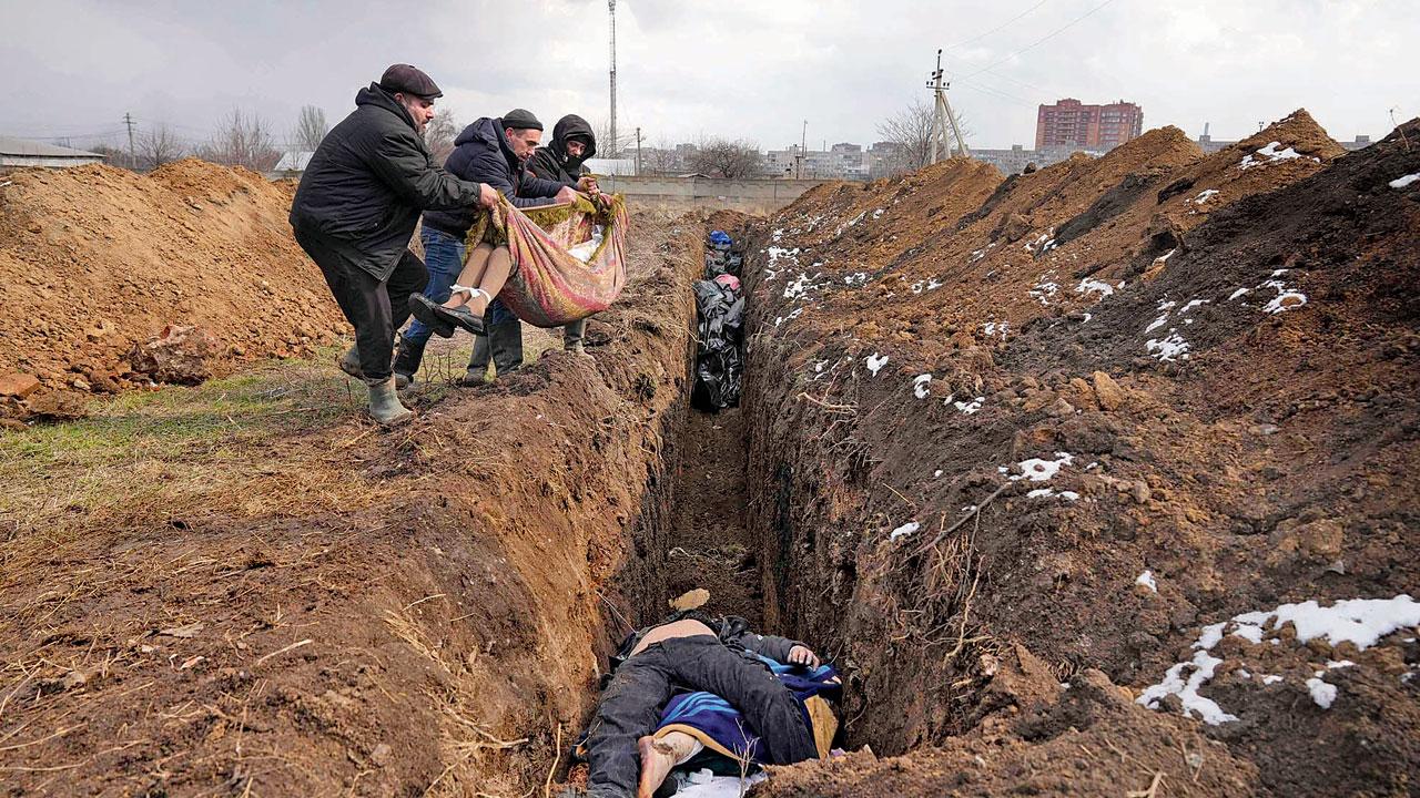 Bodies are put into a mass grave on the outskirts of Mariupol on Wednesday as people cannot bury their dead because of the heavy shelling by Russian forces. Pic/AP