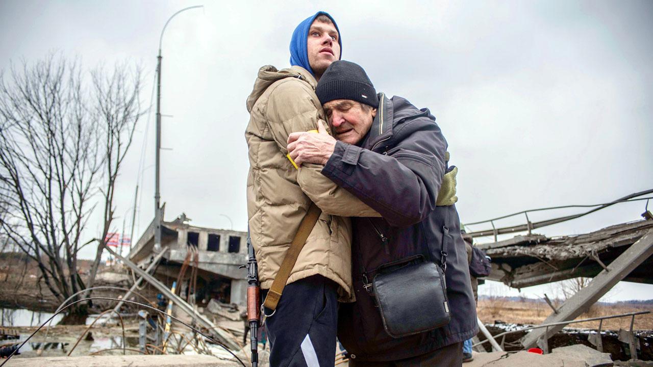 A Ukrainian Territorial Defence Forces member hugs a resident who leaves his home town following Russian shelling in Irpin. Pic/AP