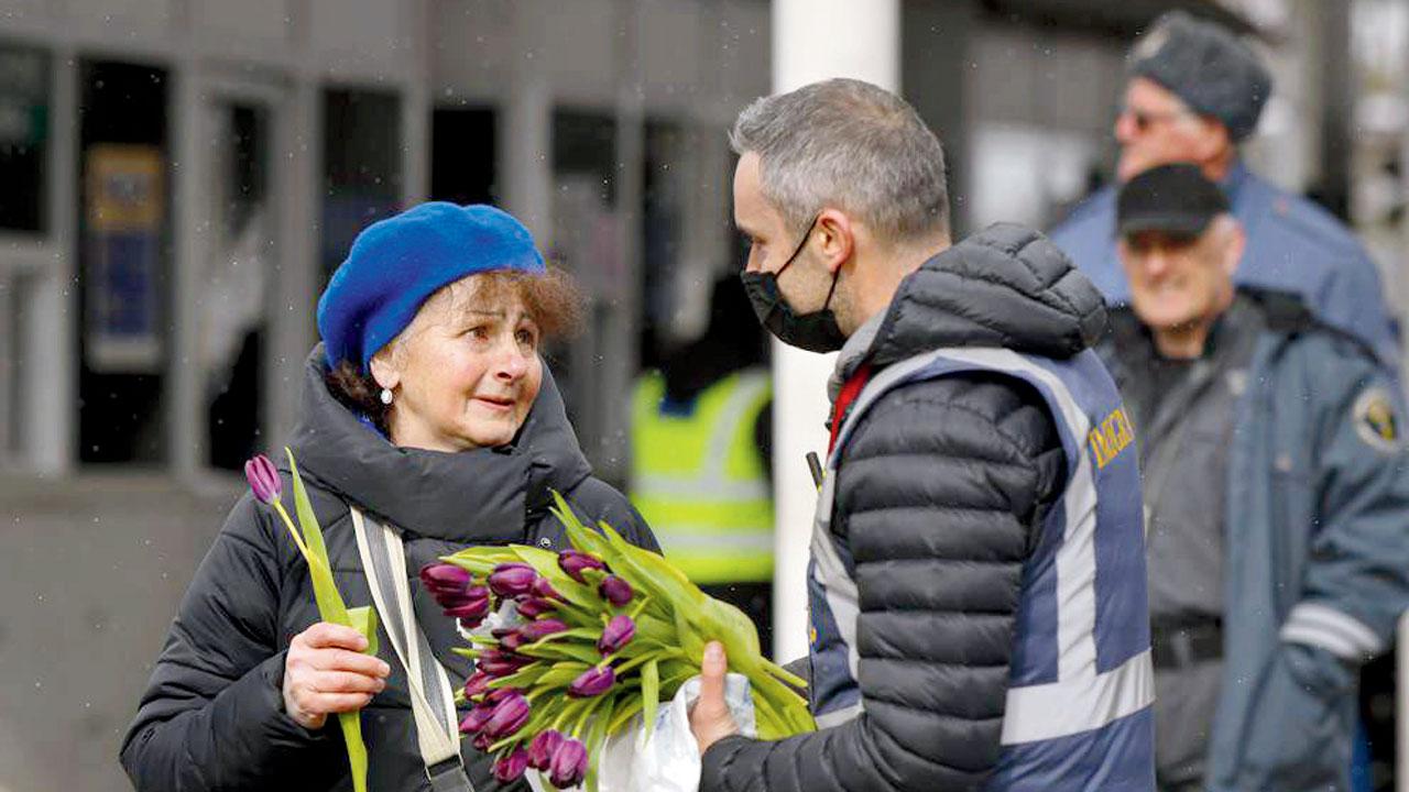 A Romanian Immigrations officer gives flowers to a refugee fleeing Ukraine on International Women’s Day, at the Romanian-Ukrainian border, in Siret on Tuesday. Pics/AP