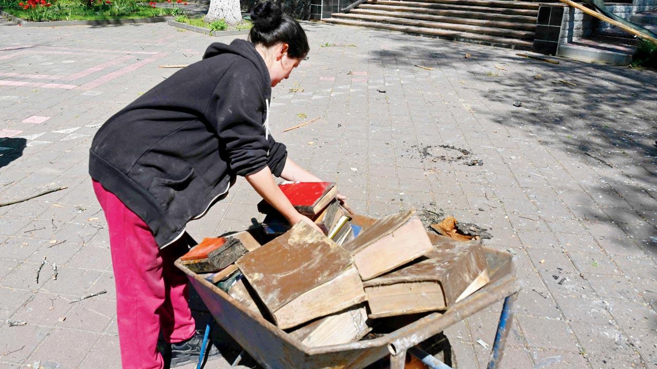 An employee collects surviving books from the museum in the 17th century manor house where  Skovoroda lived, that was destroyed after a Russian missile hit. Pics/AFP