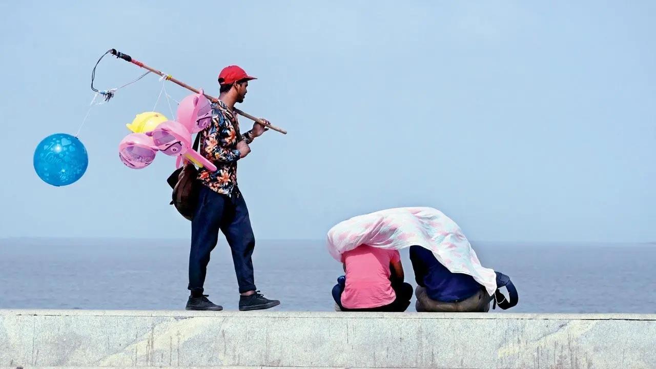 Nowhere to hide: A balloon-seller gapes at a man and woman seated at Marine Drive with a dupatta as their shield from the hot sun. Pic/Bipin Kokate