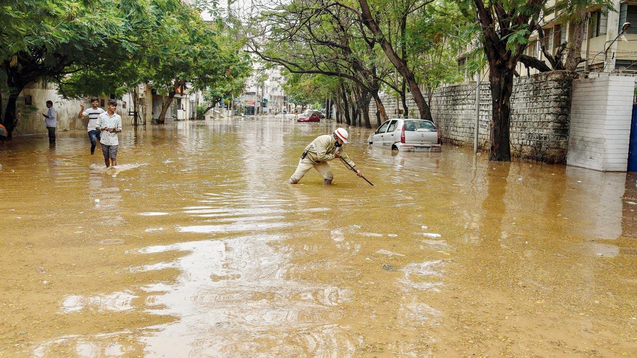 A cop clears waterlogging on a road, in Hyderabad, on Wednesday 