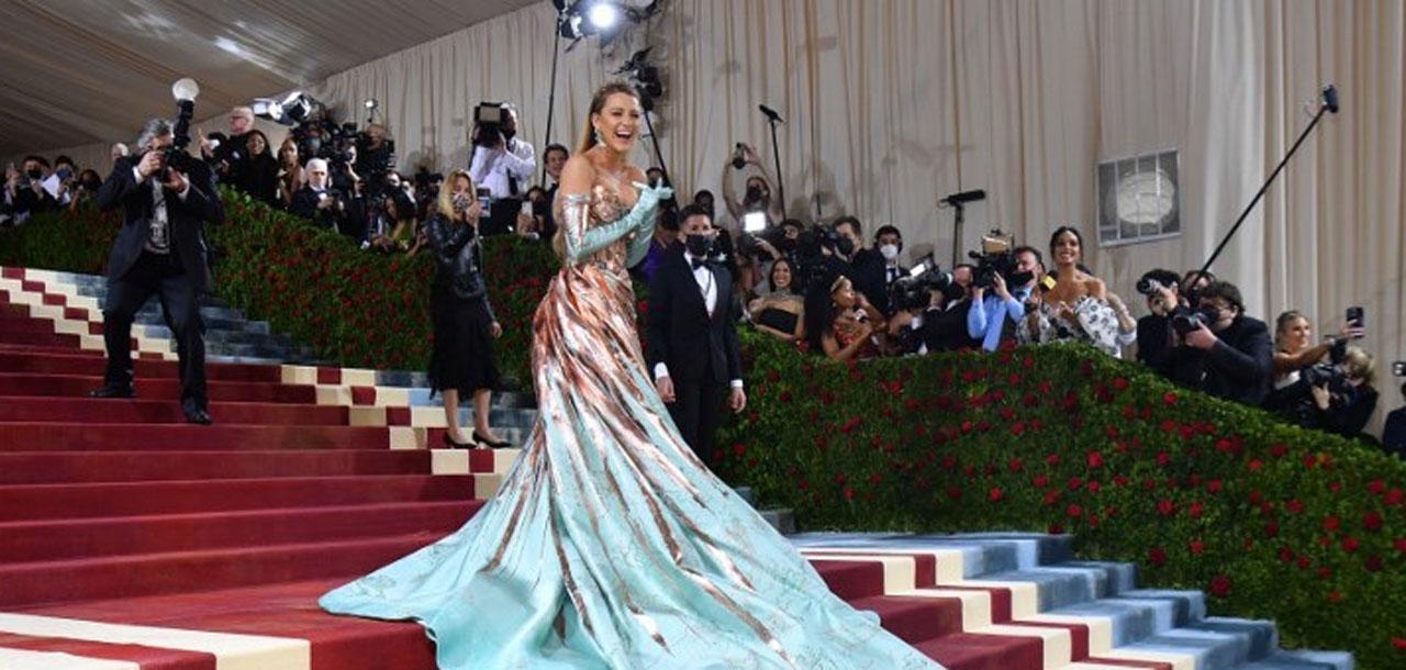 Blake Lively arrived at the Met Gala red carpet with her husband, Ryan Reynolds, wearing an embellished gown with a large bow from Versace inspired by the architecture of the Empire State Building. She transformed her gown as she walked up the grand stairs of the MET from rose gold to aqua.