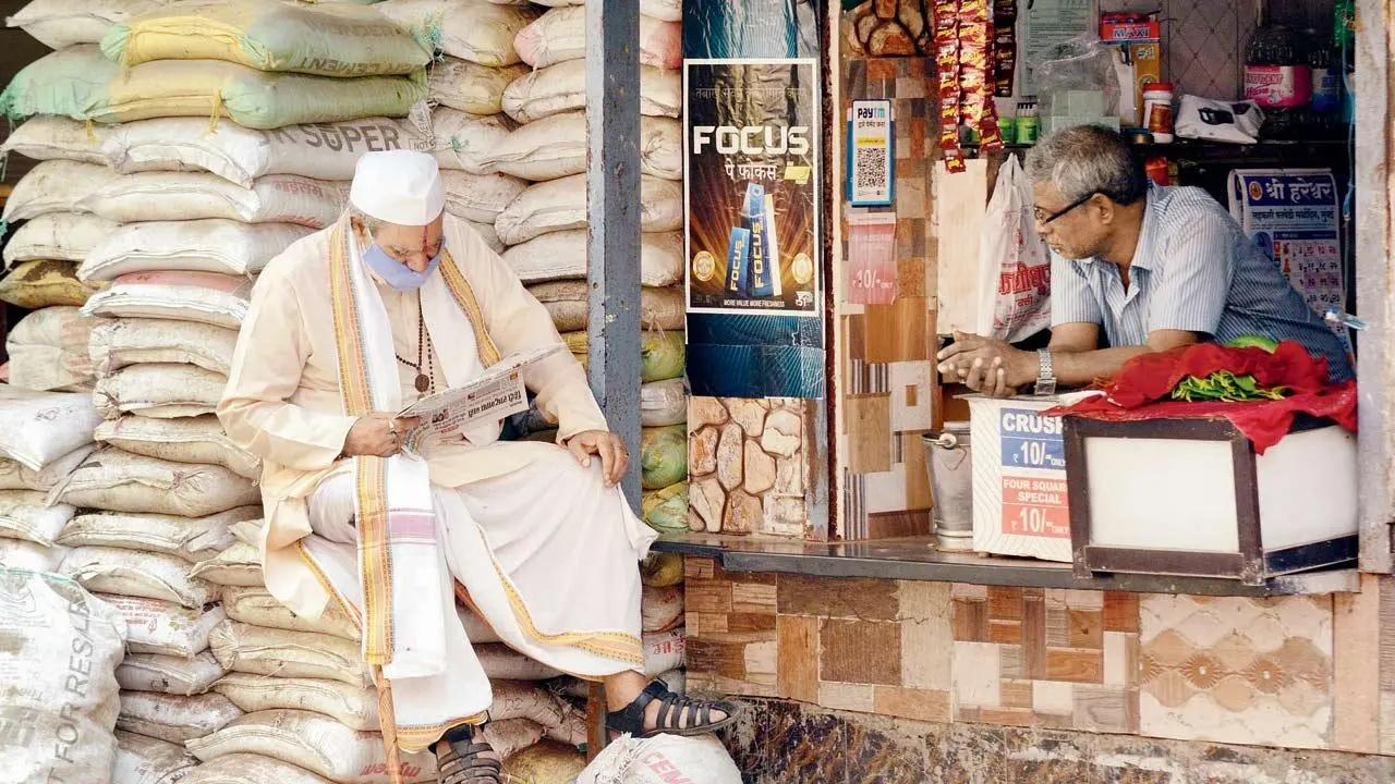 Seat of knowledge: Perched atop a mound of cement bags, an elderly man reads a newspaper outside a paan shop in Dombivli. Pic/Satej Shinde