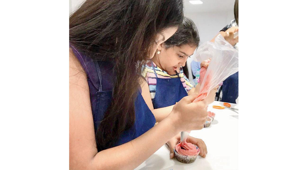 Kids decorating cupcakes by referencing chef Khan’s samples