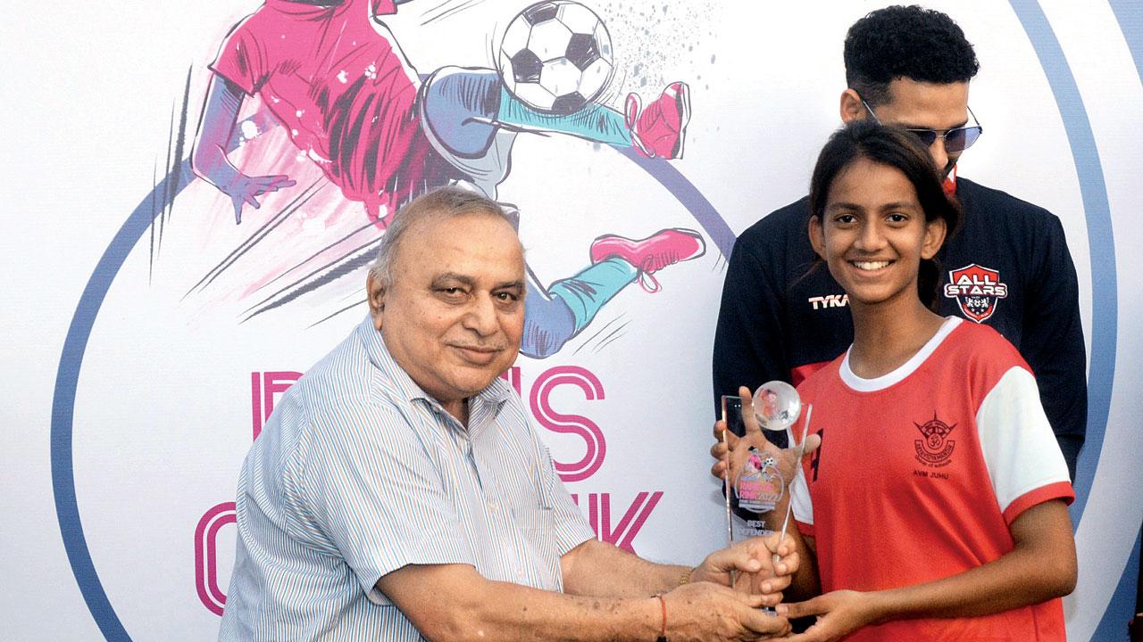 Mumbai Football Association (MFA) treasurer Udayan Banerjee gives away the Best Defender trophy to AVM Juhu’s Kavya Aher (right)