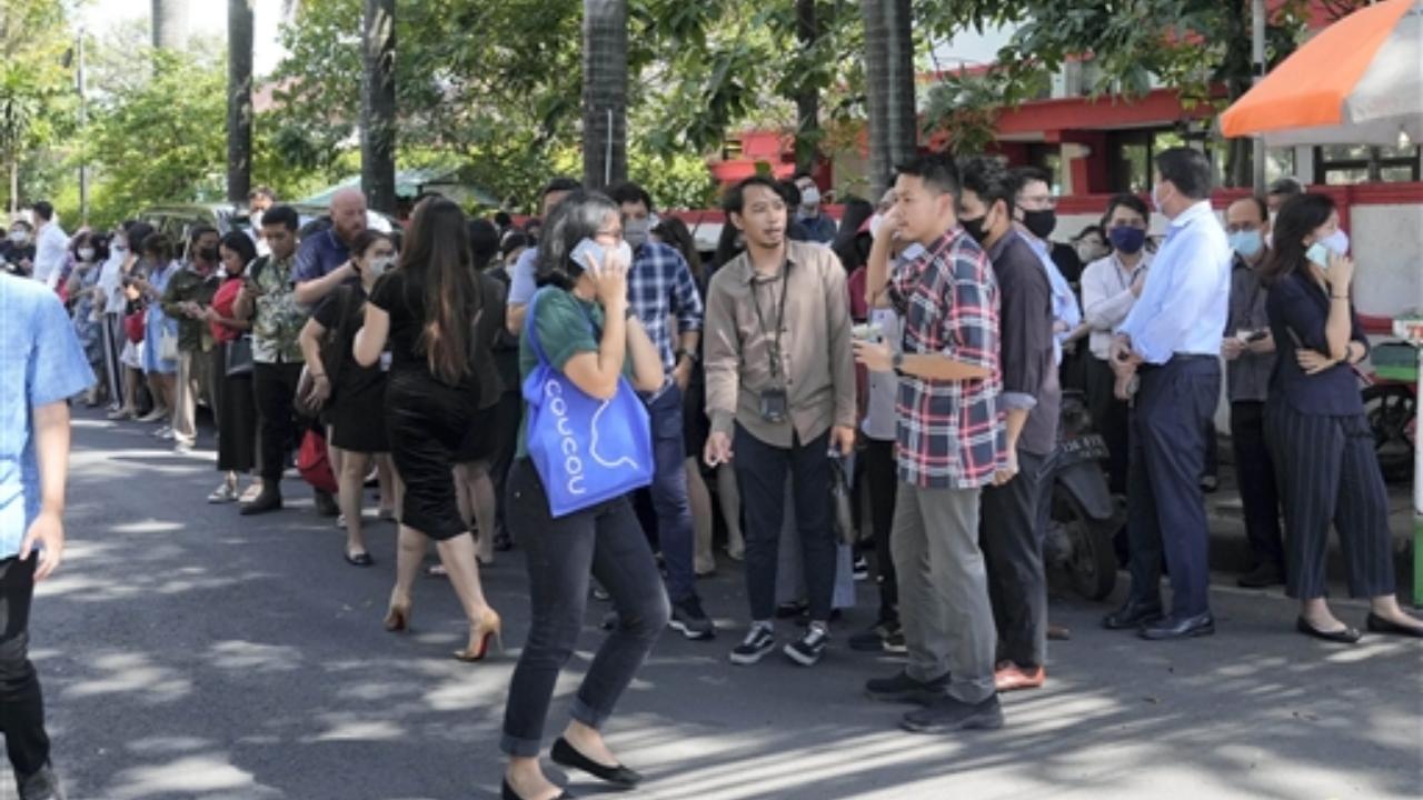 People wait outside an office building after being evacuated following the earthquake