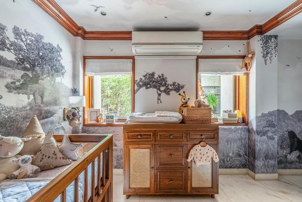 The cozy room for the little one has ample sunlight and the cradle is placed right in front of the window exposing the kid to natural sunlight and wind. The walls are painted to depict the nature