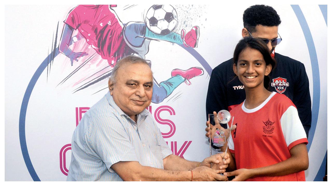 Mumbai Football Association (MFA) treasurer Udayan Banerjee gives away the Best Defender trophy to AVM Juhu’s Kavya Aher (right)